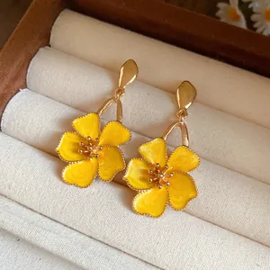Detailed view of vintage gold-tone flower drop earrings featuring yellow enamel petals