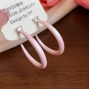 Detalle de pendientes de aro en forma de C de esmalte rosa con brillantes tachuelas de circón