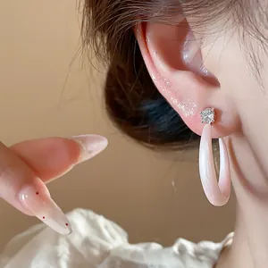 Primer plano de pendientes de aro en C de esmalte rosa con circonita en la oreja