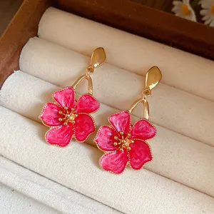 Close-up detail of vintage-style gold earrings with elegant pink enamel flower dangles.