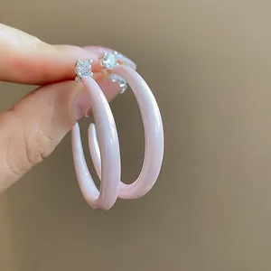 Detalle de pendientes de aro en C de esmalte rosa brillante con circonitas brillantes
