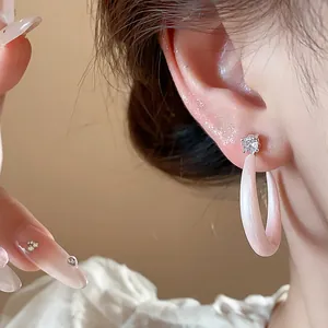 Elegante primer plano de pendientes tipo C en esmalte rosa con circonita brillante.