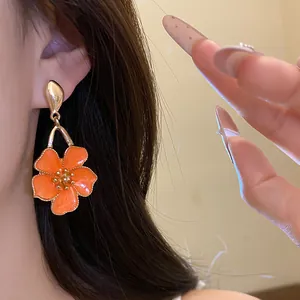 Elegant close-up of a vintage orange oil-dripping flower drop earring worn by a model