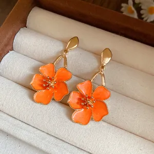 Macro detail of vintage orange enamel flower drop earrings showcased in a jewelry box