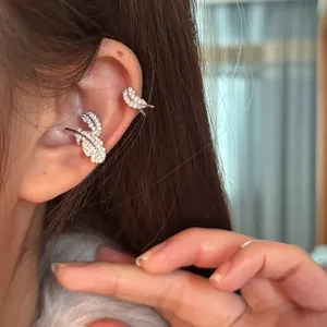 Close-up detail of sparkling zircon-encrusted silver feather ear cuffs worn on model's ear