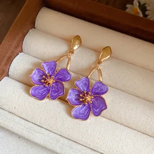 Close-up of elegant purple flower earrings with gold detailing in a jewelry box