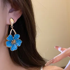Close-up of elegant blue enamel flower dangle earring with gold-toned petal details