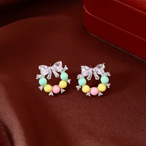 Gros plan de boucles d'oreilles couronne colorées avec nœud en zircon sur velours