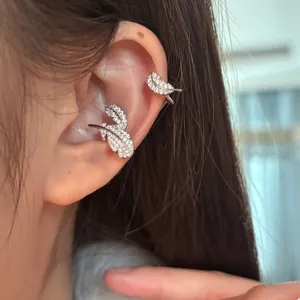 Close-up detail of elegant silver feather ear cuff earrings inlaid with sparkling zircons