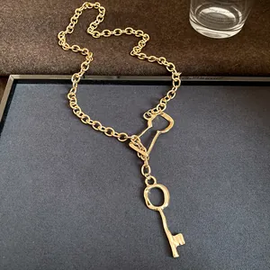 Vintage gold chain necklace featuring a unique key pendant on a minimalist display tray