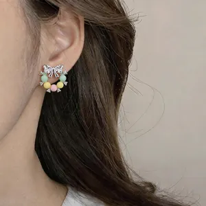 Gros plan détaillé de boucles d'oreilles nœud avec perles pastel sur tige argent