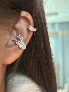 Exquisite close-up of a silver-toned zircon feather ear cuff worn on the ear bone