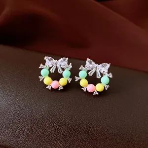Vue détaillée de boucles d'oreilles clous en couronne avec nœud et zircones étincelants