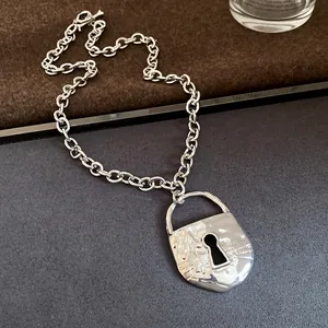 Detailed macro shot of a retro silver-colored metal chain necklace with lock pendant.