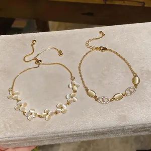Close-up of elegant gold bracelets with cat's eye flower motifs and zircon oval links.