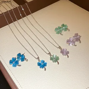 Detail of cat eye stone clover necklaces and earrings in blue, green, and pink.
