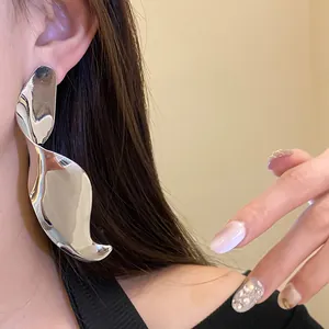 Close-up of large silver twisted geometric pendant earring on model's ear
