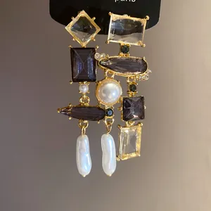 Dettaglio ravvicinato di orecchini geometrici vintage con cristalli viola e perle
