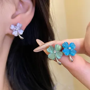 Detailed view of cat's eye stone four-leaf clover stud earrings in multiple colors
