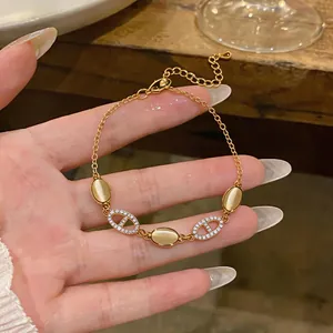 Detailed view of golden bracelet featuring oval cat eye stones and zircon-paved links.
