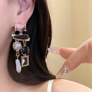 Primo piano di orecchini barocchi vintage con cristalli e perle indossati da una modella.