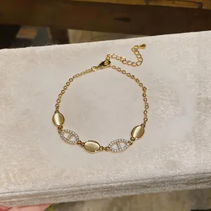 Macro detail of elegant gold bracelet featuring cat eye stones and pavé zircon oval links