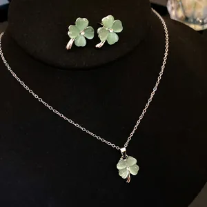 Close-up of elegant four-leaf clover cat's eye stone jewelry set on black display