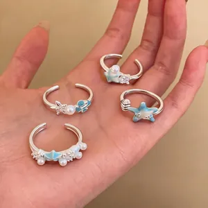 Set of four delicate starfish and shell open rings with blue enamel and pearls
