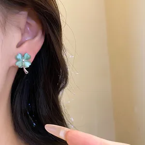 Close-up of elegant green cat's eye four-leaf clover stud earring on ear