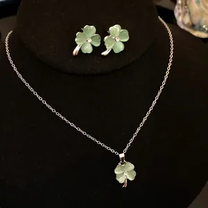Detailed view of elegant four-leaf clover jewelry set with green cat-eye stones and crystals