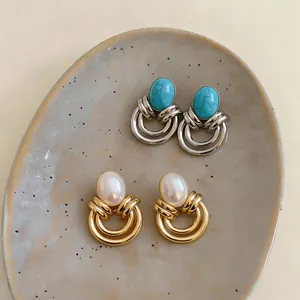 Eleganti orecchini vintage con turchese e perle su un vassoio di ceramica strutturato