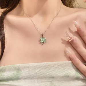 Detailed view of an elegant green cat's eye four-leaf clover necklace worn on model's neck