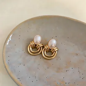 Dettaglio ravvicinato di orecchini di perle dorati stile vintage su piatto ceramico