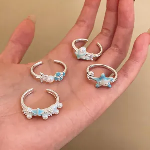 Detailed view of four starfish and shell enamel open rings with pearls and zircons