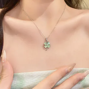Detailed macro view of silver necklace with green cat's eye clover pendant on model neck