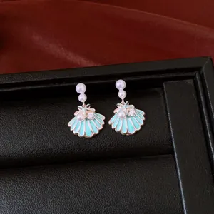 Close-up detail of light blue enamel shell earrings with pearls and zircon crystals