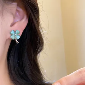 Close-up of elegant green cat-eye stone four-leaf clover stud earrings on ear