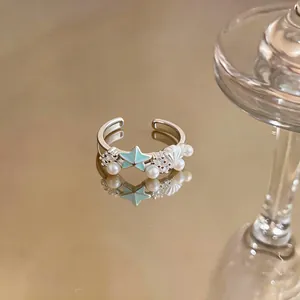Detailed view of a silver starfish and shell open ring with pearls and mint enamel.