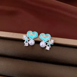 Close-up of blue heart stud earrings with starfish, pearl, and zircon details