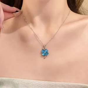 Detailed macro view of silver necklace with blue cat's eye four-leaf clover pendant on skin