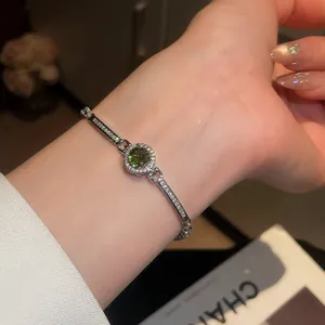 Detailed macro view of a sparkling green zircon round bracelet with silver-tone band