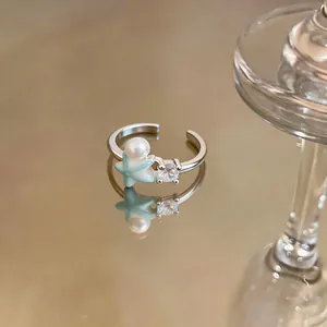 Detailed view of an open ring featuring a light blue starfish, a pearl, and a clear zircon