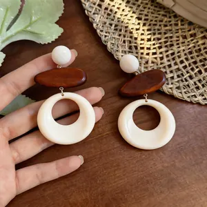 Dettaglio di orecchini geometrici retrò in legno e resina per look da vacanza