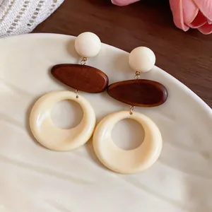 Dettaglio ravvicinato di orecchini retrò in legno e resina su un piatto di ceramica