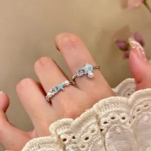 Close-up of elegant starfish and shell open rings with zircon and pearls on finger