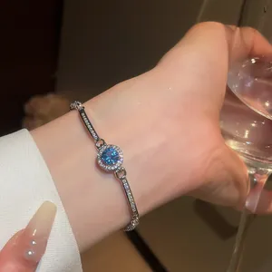Detailed view of silver bracelet with blue zircon center and halo of clear stones