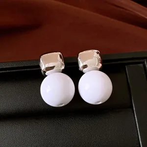 Detalle macro de pendientes de tuerca retro cuadrados plateados y esferas de resina blanca