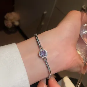 Close-up of elegant silver bracelet with round purple zircon on a woman's wrist.