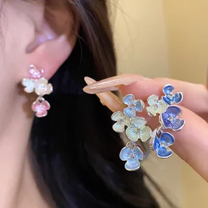 Dettaglio macro di orecchini a fiore stile coreano con strass e smalto dai toni pastello