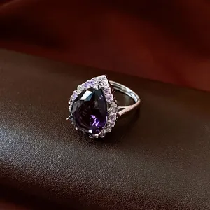 Eleganter Silberring mit lila Zirkonia in Tropfenform und Halo-Fassung auf Leder